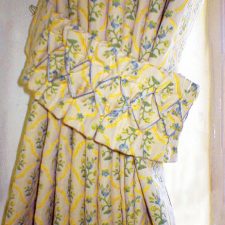 Yellow, blue and green patterned curtains with matching tie back